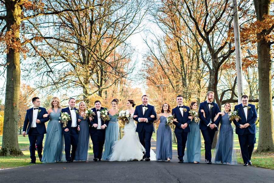 A happy wedding party walk arm in arm and laugh.